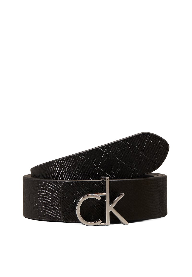 Sort læderbælte med præget mønster, der har en sølvfarvet spænde med "CK" logo. Glat overflade, flad form og justerbar længde.