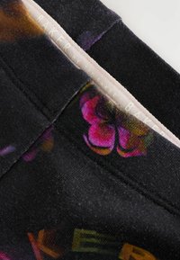 Čierna tkanina s kvetinovým vzorom v odtieňoch ružovej a fialovej. Obsahuje mäkký pás s brandingom "Ted Baker" v svetlej farbe.