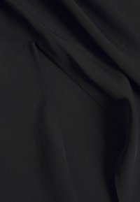 Černá tkanina, hladká textura, splývavý vzhled. Má měkký, lehký materiál s jemným leskem a mírným elastickým efektem.