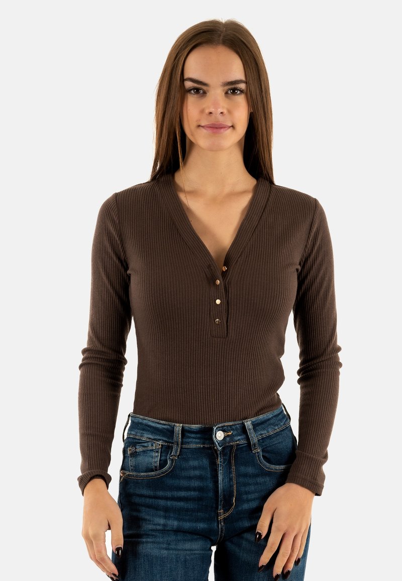 Haut à manches longues rayé marron avec un col en V et une patte de boutonnage à trois boutons, associé à un jeans en denim bleu. Texture lisse et design ajusté.