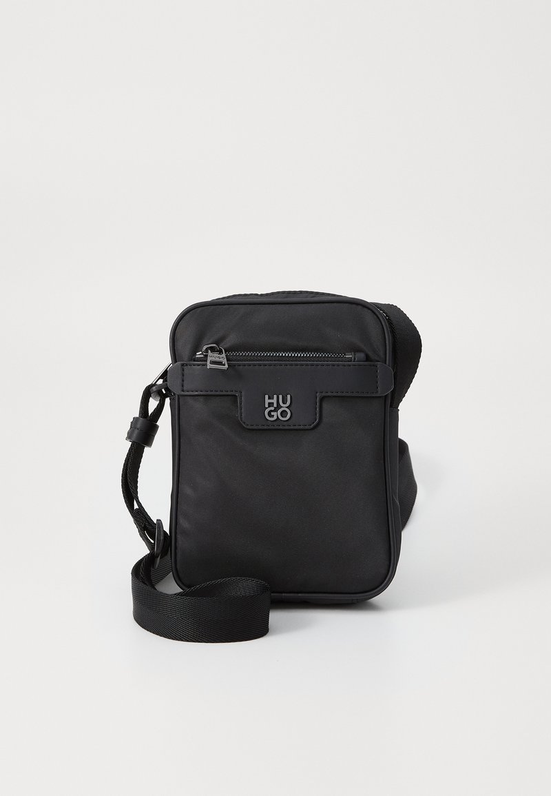 Sorte nylon crossover taske med rektangulær form, der har en frontlynlås lomme, justerbar rem og et hævet logo detalje.