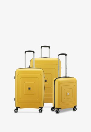 Drie gele harde koffers in verschillende maten met zwarte accenten, gestructureerde oppervlakken, uitschuifbare handvatten en 360 graden draaibare wielen.