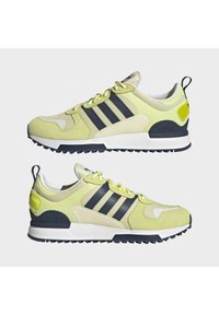 Lime green athletic shoes with navy stripes, suede and mesh materials, rubber sole, padded collar, and contrasting heel detail.