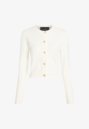 Balta, trumpa megztinė pagaminta iš minkštos megztos medžiagos, su ilgomis rankovėmis ir šešiais auksinės spalvos mygtukais priekyje.