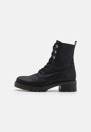 Bottines noires en matériau texturé, dotées de six œillets, d'un bout rond et d'un robuste talon bloc avec une semelle robuste.