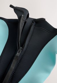 Neoprénová neoprénová kombinéza v čiernej a tyrkysovej farbe. Má stredový zips s čiernou páskou, textúrovanú podšívku a hladké panely pre flexibilitu.
