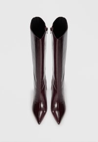 Burgundowe skórzane kozaki do kolan z ostrym noskiem i eleganckim designem. Posiadają zamek z tyłu, co ułatwia zakładanie.