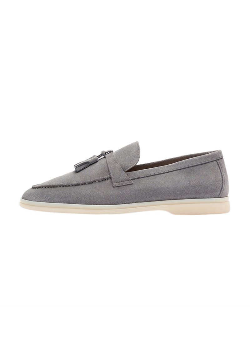 Mocassini grigi in suede con punta rotonda, nappine decorative e suola in gomma crema a contrasto. Design elegante con dettagli di cucitura minimi.