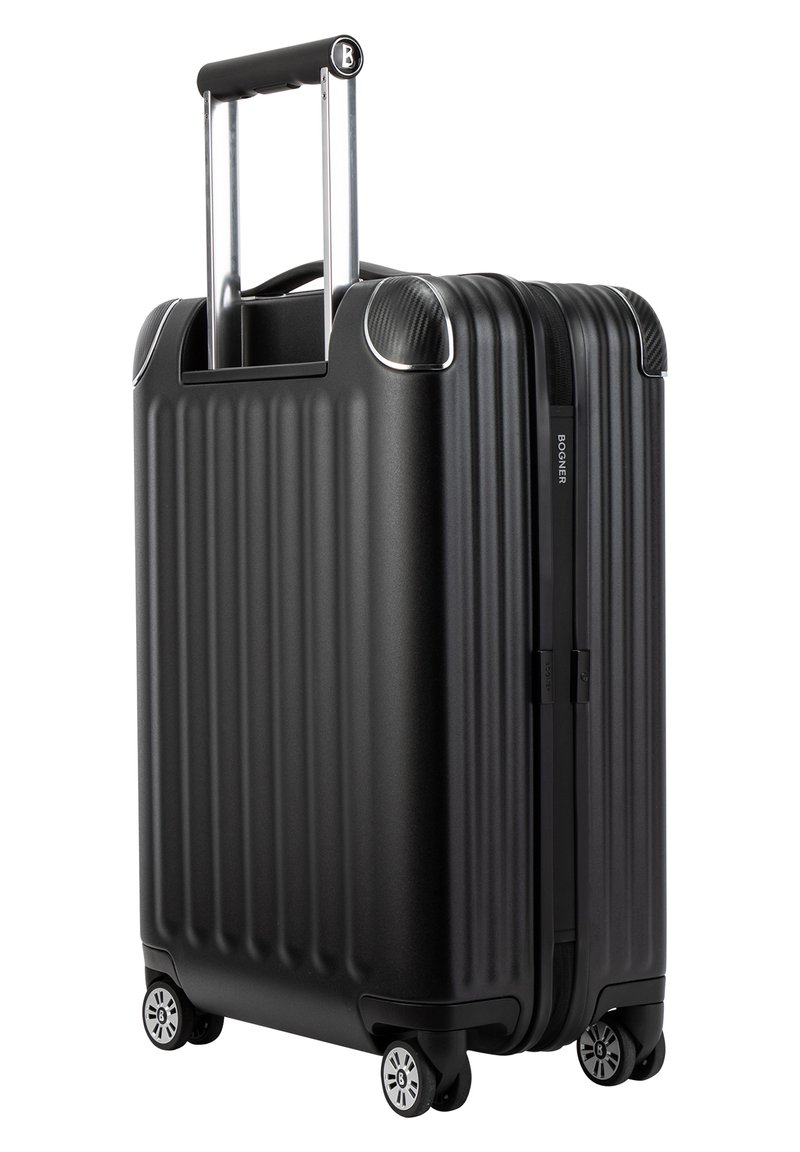 Schwarzer Hartschalenkoffer mit vertikaler Rippstruktur, ausziehbarem Griff und vier Rollen. Verfügt über silberne Akzente und einen Reißverschluss.