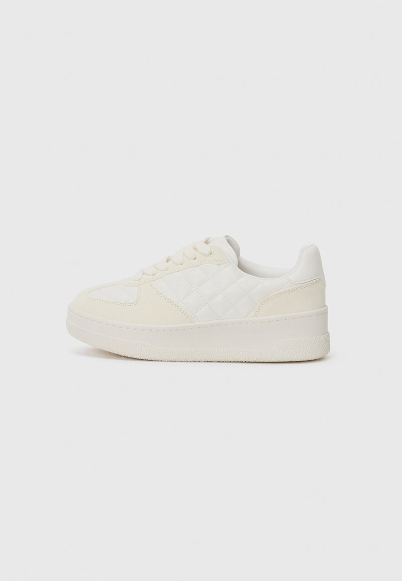 Sneaker bianco con pannello laterale trapuntato, lacci piatti, collare imbottito e suola in gomma texturizzata, con punta arrotondata e finitura liscia.
