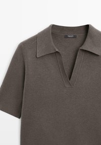 Maglione a maniche corte con scollatura a V in tessuto knit grigio scuro. Presenta un colletto piatto e una superficie liscia con un design minimalista.