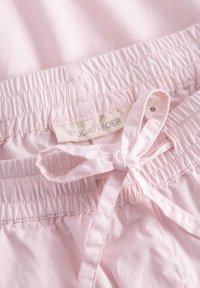 Lichtroze shorts van zachte stof, met een elastische tailleband en een trekoordsluiting, voorzien van een label met de tekst "STUDIO FEDER."