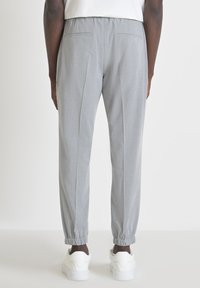 Pantalons gris clair à taille élastique, avec poches latérales et poignets côtelés. Texture lisse avec une coupe fuselée pour le confort et la liberté de mouvement.