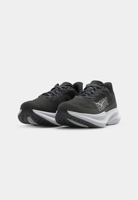 Des chaussures de sport noires avec une tige texturée, dotées d'un intercalaire blanc et d'un logo bien visible sur le côté. Tissu en maille pour la respiration.