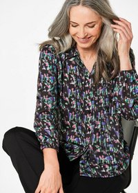 Camicia con bottoni in un tessuto nero con un motivo astratto multicolore. Presenta maniche lunghe con polsini elasticizzati e una vestibilità rilassata.