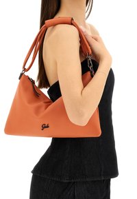 Borsa a mano in pelle arancione con forma triangolare e texture liscia, dotata di dettaglio logo e doppi manici per la spalla.