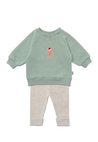 Green sweatshirt with gingerbread man print, paired with light gray ribbed pants, featuring rolled-up cuffs and soft fabric texture.