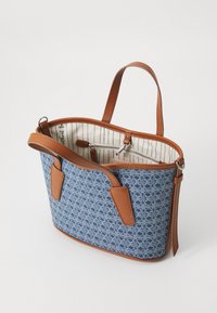 Denimblå totebag med brune lærrelementer, med et mønstret ydre, åben top og indvendig lomme med lynlås og stribet for.