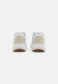 Athletic sneakers featuring a light blue, beige, and white color scheme, with a textured upper and a cushioned white sole.