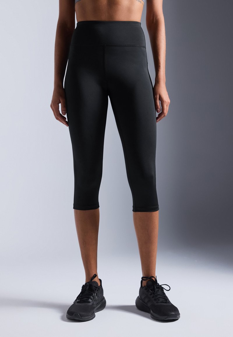 Leggings Capri noirs taille haute fabriqués dans un matériau extensible, présentant une texture lisse et un design ajusté, se terminant juste en dessous du genou.
