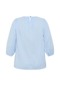 Vaaleansininen paita, jossa on pilkullinen kuvio, 3/4-pituiset hihat, gathered-olkapäät ja avainaukko takana pienellä napilla.