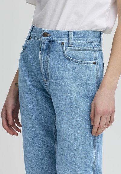 Vaqueros de un azul claro hechos de denim, con cintura alta, cinco bolsillos, cierre de botón de metal y detalles de costura sutiles.