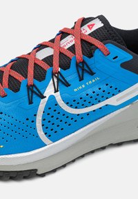 Scarpa da trail running Nike in blu con tomaia in rete a motivo, dettagli argentati, lacci rossi e suola nera texturizzata per una migliore trazione.