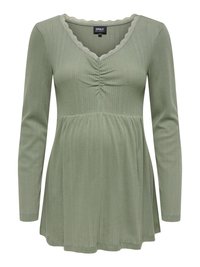 Green long-sleeve top with a V-neck and scalloped lace trim. Features vertical ribbed texture and gathered detail under the bust.