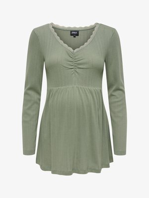 Roheline pikakarvaline pluus V-kaelusega ja lainelise pitsäärisega. Omab vertikaalset soonilist tekstuuri ja pooleldi kogutud detaili rinna all.