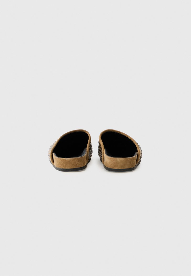 Braune Wildlederslipper mit offener Ferse und strukturiertem gewebtem Detail an der Seite. Flache Sohle mit matter Oberfläche. Das Innere ist schwarz.
