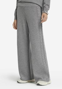 Pantalons larges gris en tricot doux avec des détails en tricot torsadé le long des côtés. Dotés d'une taille élastique et de poignets côtelés.