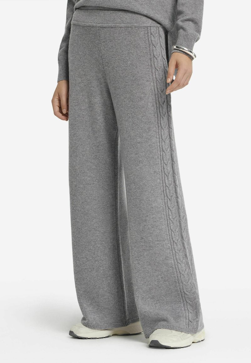 Pantalons larges gris en tricot doux avec des détails en tricot torsadé le long des côtés. Dotés d'une taille élastique et de poignets côtelés.