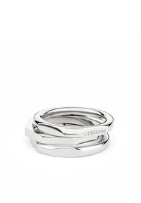 Bagues empilées en argent avec des bords lisses et arrondis et un design géométrique. Présente le nom de marque en relief sur une des bagues.