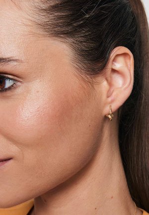 Złote kolczyki w kształcie obręczy z małym akcentem motyla. Kolczyki mają gładką teksturę i polerowane wykończenie, co podkreśla ich delikatny design.