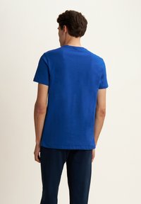 T-shirt in cotone blu royal con maniche corte e scollatura rotonda, caratterizzato da un design semplice e un fit rilassato. Viene mostrato il retro.