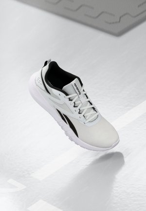 Baskets de sport blanches avec accents noirs, dessus en mesh respirant, design à lacets et semelle intermédiaire texturée pour un amortissement. Construction légère.