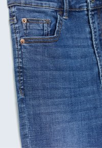 Jeans de denim azul con un diseño clásico de cinco bolsillos, remaches de cobre y costuras en contraste. Textura suave con un acabado deslavado.