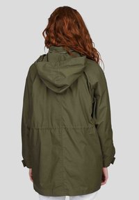 Veste imperméable vert olive avec une capuche, taille élastique et manches longues. Présente une texture lisse et des détails de couture contrastés.