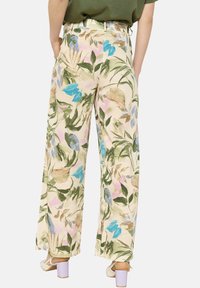 Floral wide-leg pants in light fabric feature a beige base with blue, pink, and green leaf patterns, designed with a high waist.