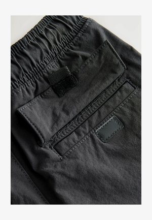 Juodi šortai su elastinga juosmens juosta, tekstūruotu audiniu ir kišene su velcro uždarymu, išryškinančia siuvinėjimo detales.