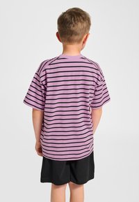 Lila gestreiftes T-Shirt aus weicher Baumwolle mit schwarzen horizontalen Streifen, legerem Schnitt und kurzen Ärmeln. Wird mit schwarzen Shorts getragen.