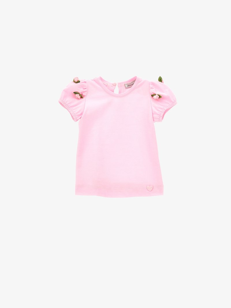 T-shirt di cotone rosa con maniche corte a sbuffo, con dettagli floreali e un logo a forma di cuore nella parte inferiore. Collo rotondo con chiusura a bottone.