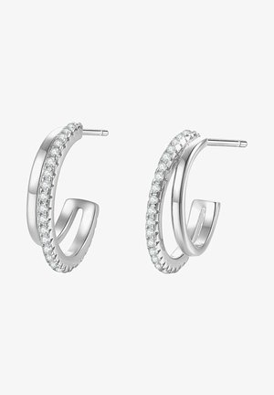 Srebrne kolczyki na kółku z teksturowanym wzorem oraz rzędem małych, przezroczystych kamieni wzdłuż zewnętrznej krawędzi. Gładkie, polerowane wykończenie.