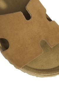 Sandale à glissière en daim marron présentant un design découpé, une texture douce et une semelle intérieure rembourrée pour le confort. Semelle circulaire pour la stabilité.