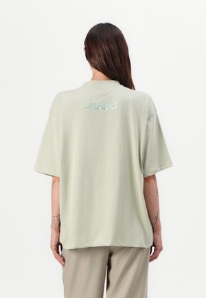 Lichtgroene oversized t-shirt van zachte stof, met een ronde hals en rugtextlogo in reflecterend materiaal. Korte mouwen.