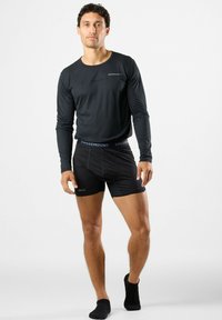 Black long-sleeve top and black boxers with a textured waistband. The top features a small logo; both are made from a smooth, stretch fabric.