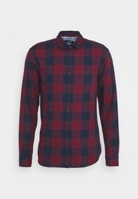 Camicia a maniche lunghe a quadri rossi e blu con chiusure a bottone, colletto classico e una texture in tessuto morbido. Motivo simmetrico su tutta la superficie.