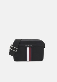 Borsa a tracolla nera con finitura testurizzata, dotata di chiusura con zip e tre strisce verticali bianche e rosse. Include una tracolla regolabile.