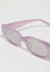 Lunettes de soleil transparentes violettes avec une monture rectangulaire et des verres légèrement teintés ; présentent une texture lisse et des bords arrondis.