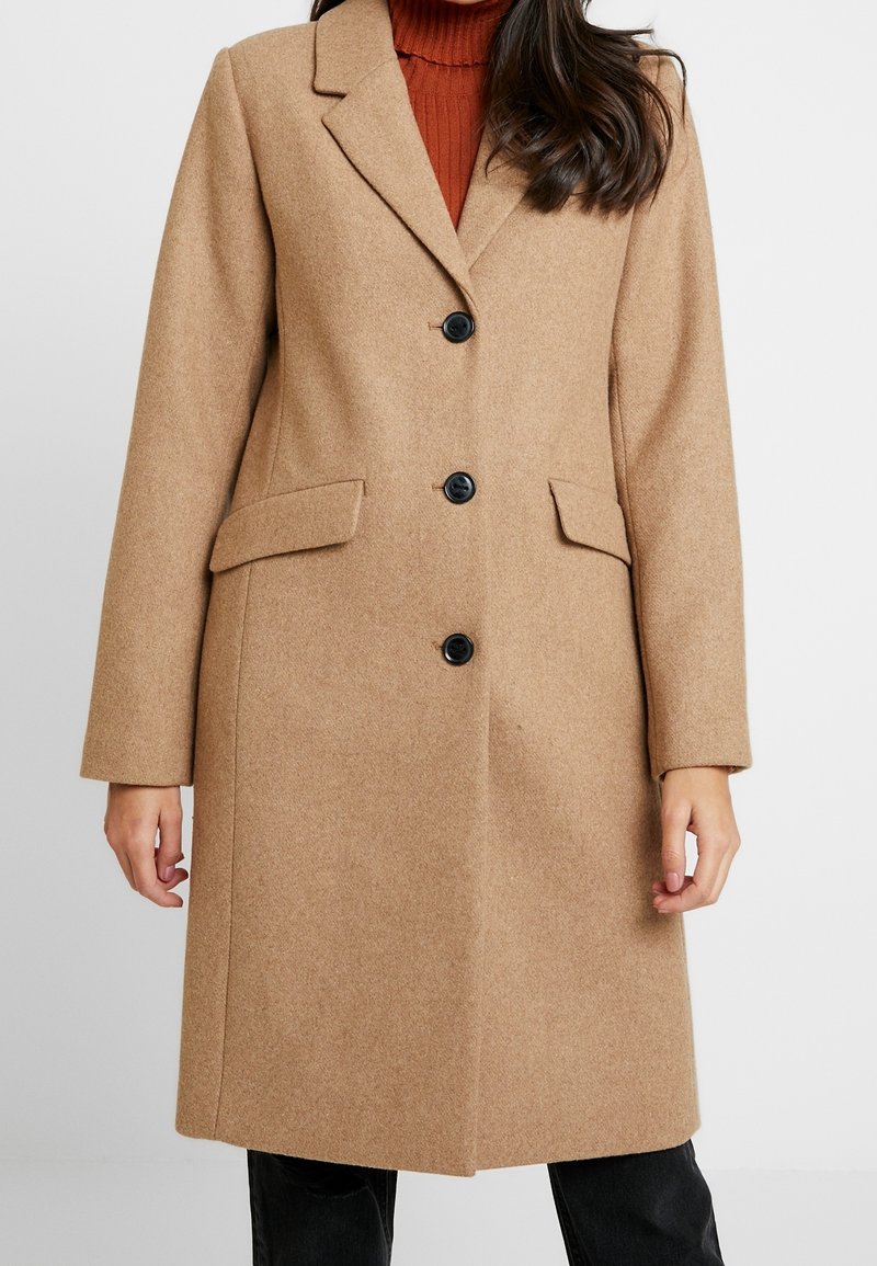 Cappotto in misto lana marrone con design sartoriale, reverse a punta, tre bottoni neri e due tasche laterali. Finitura liscia e strutturata.